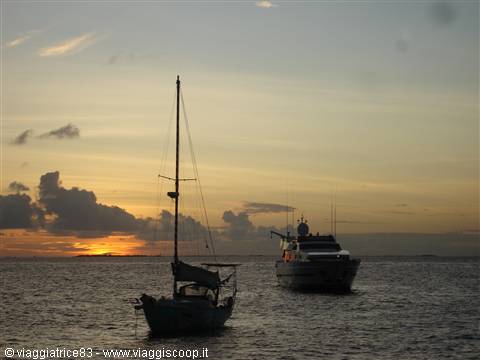 Sailboat and motor yacht anchored offshore at dusk