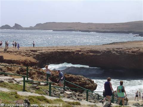 Tourists descending toward the old coral rock bridge over the ocean, Aruba