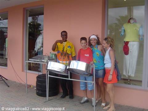 Steel drum musician posing with three tourists outside shops