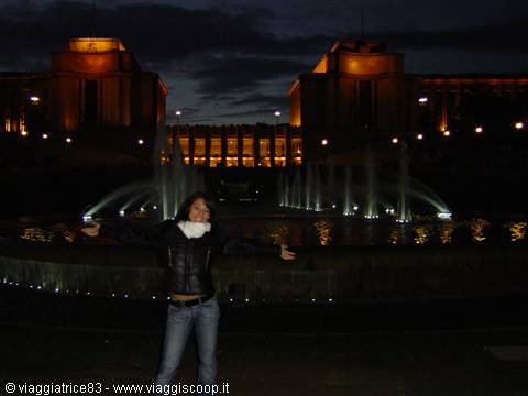 Girl with open arms in front of the illuminated Trocadéro fountains at night