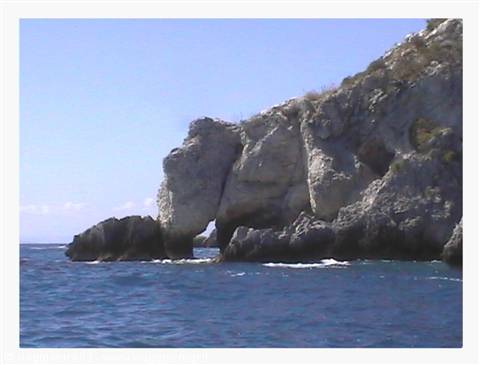 Limestone rock rising from blue sea, white cliffs under sun