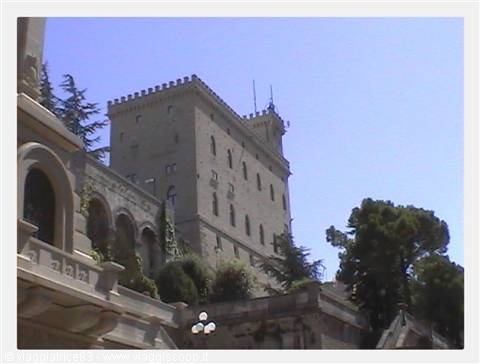 San Marino's Public Palace stone tower rising above trees and arcade