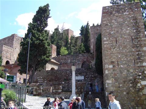 Tourists climb the stone walls of the Alcazaba of Malaga among cypresses