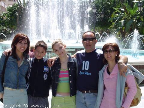 Group of friends and family posing beside a fountain with jets among palm trees