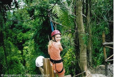 Woman in red helmet and harness on a zipline in the jungle