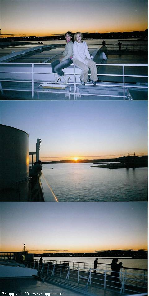 Two women sitting on ferry deck at sunset over the bay