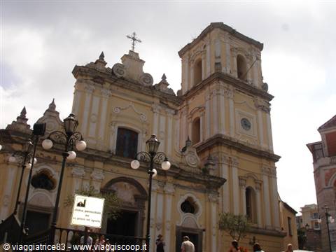 Yellow baroque church facade with bell tower, tourists below