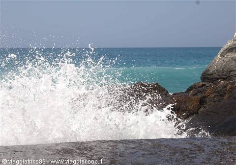 Waves crashing with white spray against black rocks by the sea
