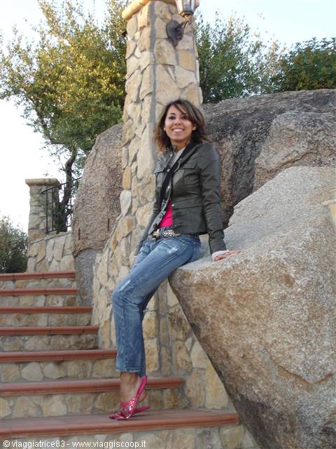 Smiling woman leaning on a granite boulder beside a stone staircase
