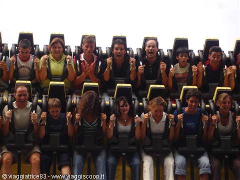People scream on a roller coaster, strapped in yellow and black seats
