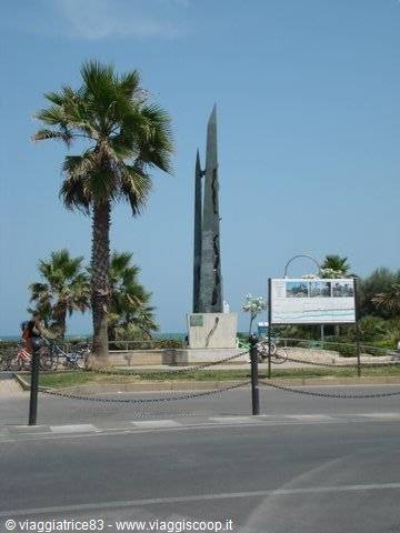 Steel monument on the seafront, palm trees and parked bicycles