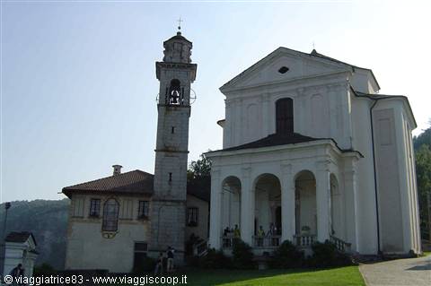 White church with columned portico and old stone bell tower among green hills