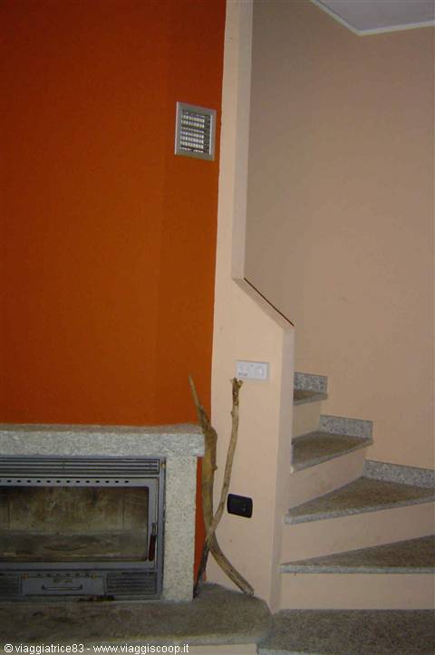 Granite fireplace under orange wall, next to indoor marble staircase