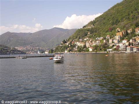 Boat on Lake Como, colorful houses along the green shoreline