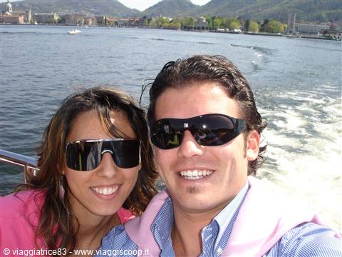 smiling couple in sunglasses on a boat, Lake Como in the background