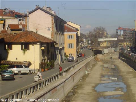 Towpath along the drained Naviglio canal in Milan, yellow houses and traffic