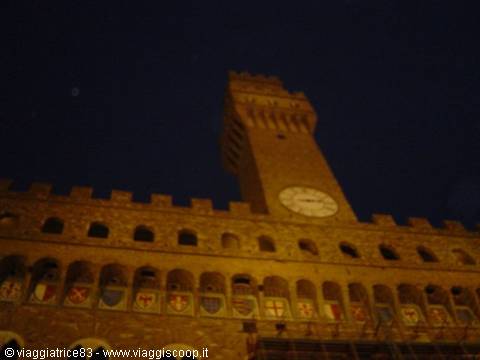 Palazzo Vecchio at night in Florence, lit tower with battlements and coats of arms