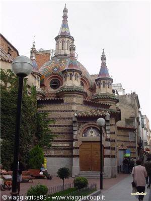 Church with colorful mosaic domes among street lamps, pedestrians walking by