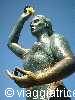 Bronze statue lifting a golden sphere against the blue sky