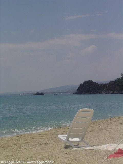 White plastic beach chair on the sand facing turquoise sea