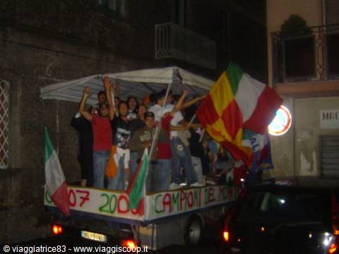 Fans celebrating on a truck waving Italian flags and 2007 championship banners