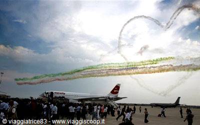 Plane on tarmac with tricolor smoke forming a heart, spectators watching