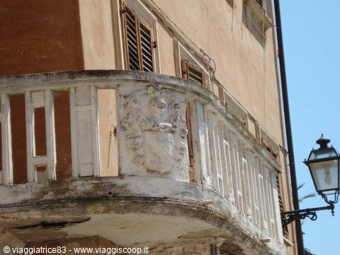 Stone balcony with carved coat of arms on ochre facade, old lantern