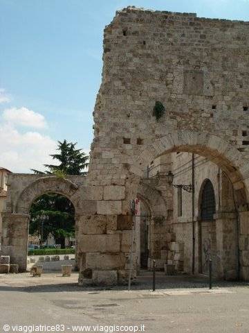Ancient stone city gate with Roman arches under blue sky