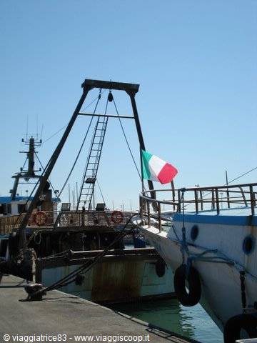 Fishing boat with Italian flag moored at the harbor, blue sky