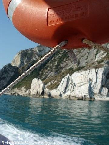 Orange lifebuoy on the boat in front of white cliffs at Monte Conero