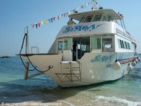 White ferry 'Simba' with colorful flags anchored near a sandy beach