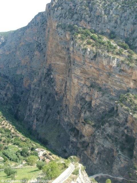 limestone cliffs of Gole del Sagittario rising above a village with olive groves
