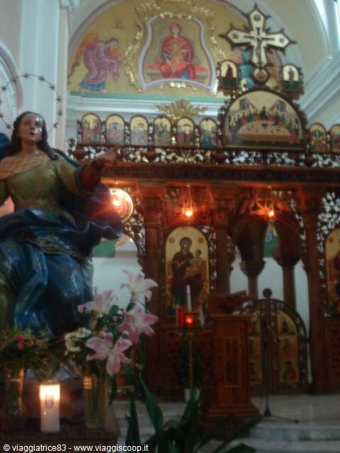 Madonna statue with flowers and candle before the wooden iconostasis