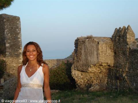 Smiling woman beside the ancient stone walls of a medieval castle