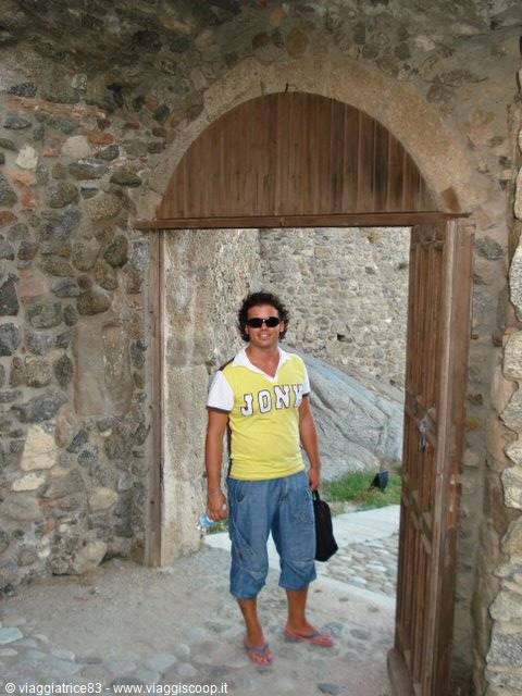Man in yellow shirt under the wooden gate of an old stone wall