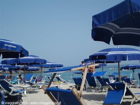 Petragrande beach, blue umbrellas on light sand, sun loungers and sea