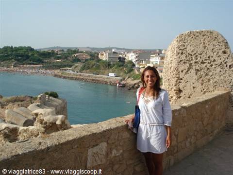 Woman in white by stone walls above Otranto bay
