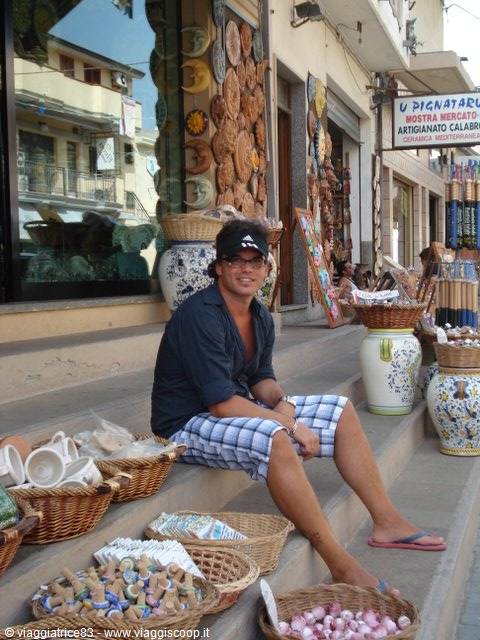 Tourist sitting among wicker baskets and ceramics outside U Pignataru shop, Tropea