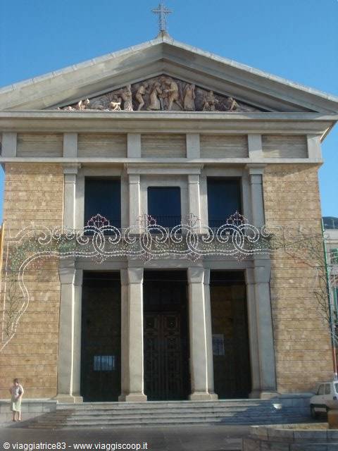 Stone facade of Reggio Calabria Cathedral with sculpted pediment and festive lights