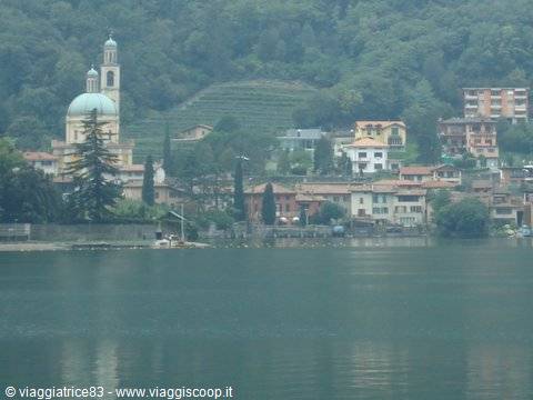 Lakeside village with bell tower and green dome among houses