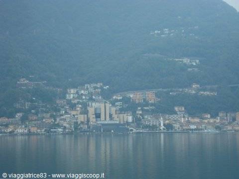 Lakeside town with colorful houses, misty green hills rising behind