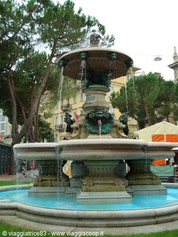 historic stone fountain with tiered basins and water jets among trees