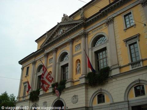 Yellow theater facade with columns, statues and waving flags