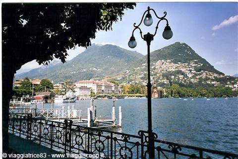 Lugano lakefront: iron railing, street lamp and pier over the water