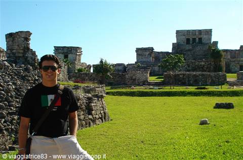 Smiling tourist in front of the Mayan stone ruins of Tulum
