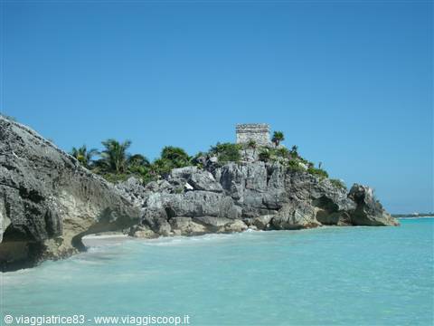 Ancient Mayan stone temple on the cliff above Tulum's turquoise sea