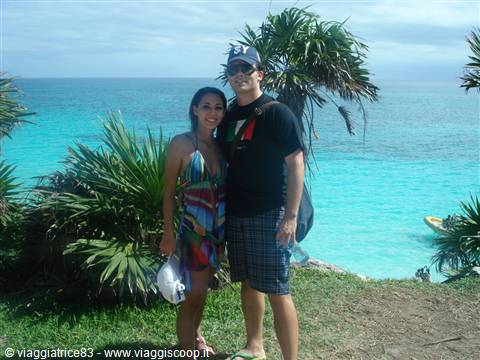 smiling couple among palms and bushes in front of turquoise sea
