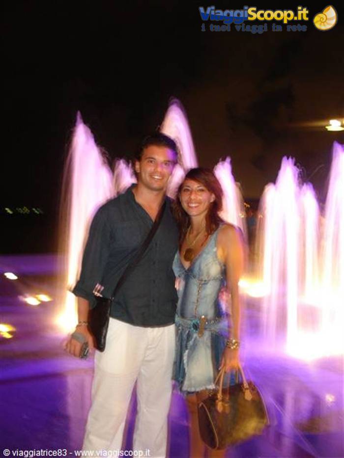 Smiling couple in front of the purple-lit fountain at night
