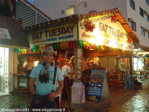 Traveler in cowboy hat in front of the neon-lit Fat Tuesday bar