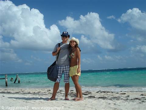 Couple on white sand beach in front of turquoise sea under clouds